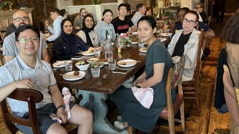 Members of the Karchin Lab gathered around a long table at a group dinner.